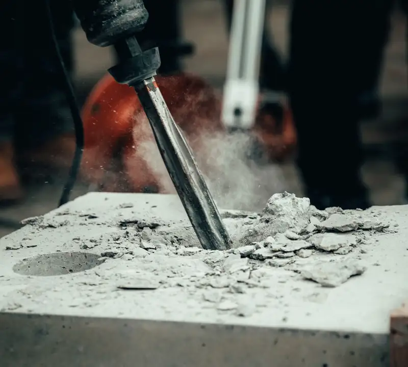 Jackhammer chisel breaking out damaged concrete before a repair pour
