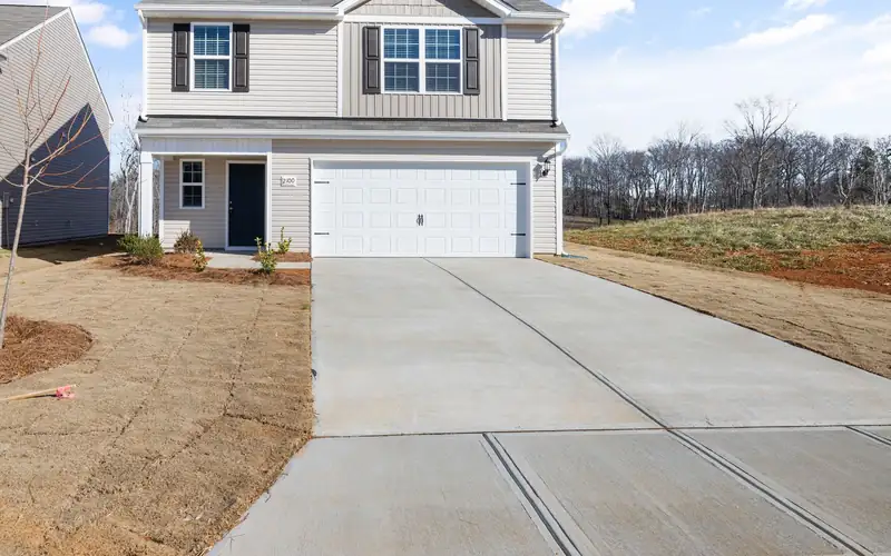 Fresh concrete driveway meeting the public sidewalk in front of a new two-story suburban house