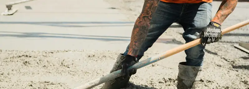 Flatwork crew raking wet concrete into place behind a new curb on a commercial site