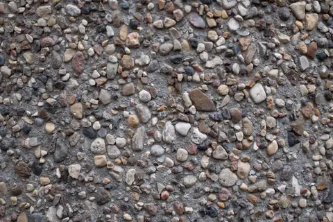 Close view of exposed-aggregate concrete with brown and gray river rock showing at the surface