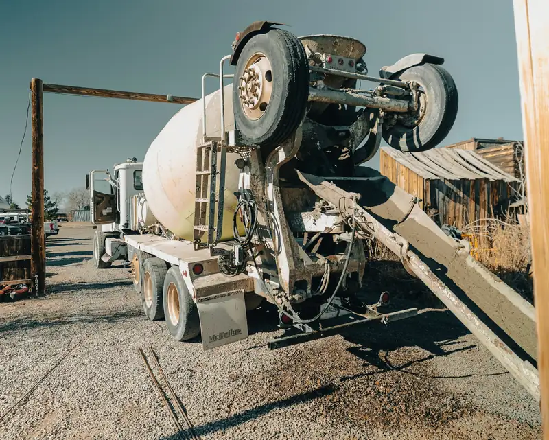 Ready-mix truck with its chute swung toward the forms on a gravel job site