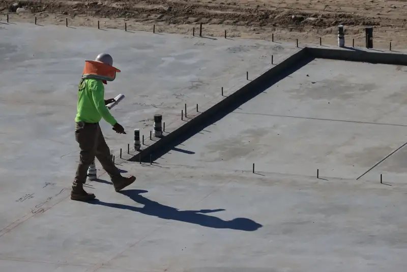 Finished slab-on-grade house foundation with plumbing stub-outs and anchor bolts along the edge