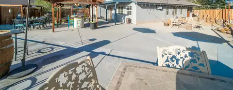 Backyard concrete patio with a textured stamped border band in the foreground and sawn joints beyond