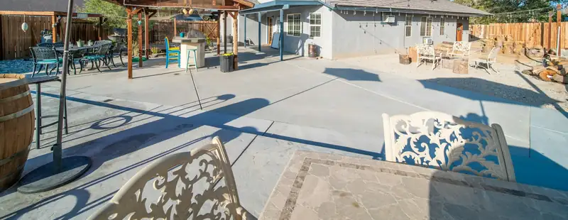 Backyard concrete patio with a textured stamped border band in the foreground and sawn joints beyond