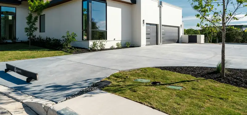 Extra-wide concrete driveway with control joints sweeping past a modern white house